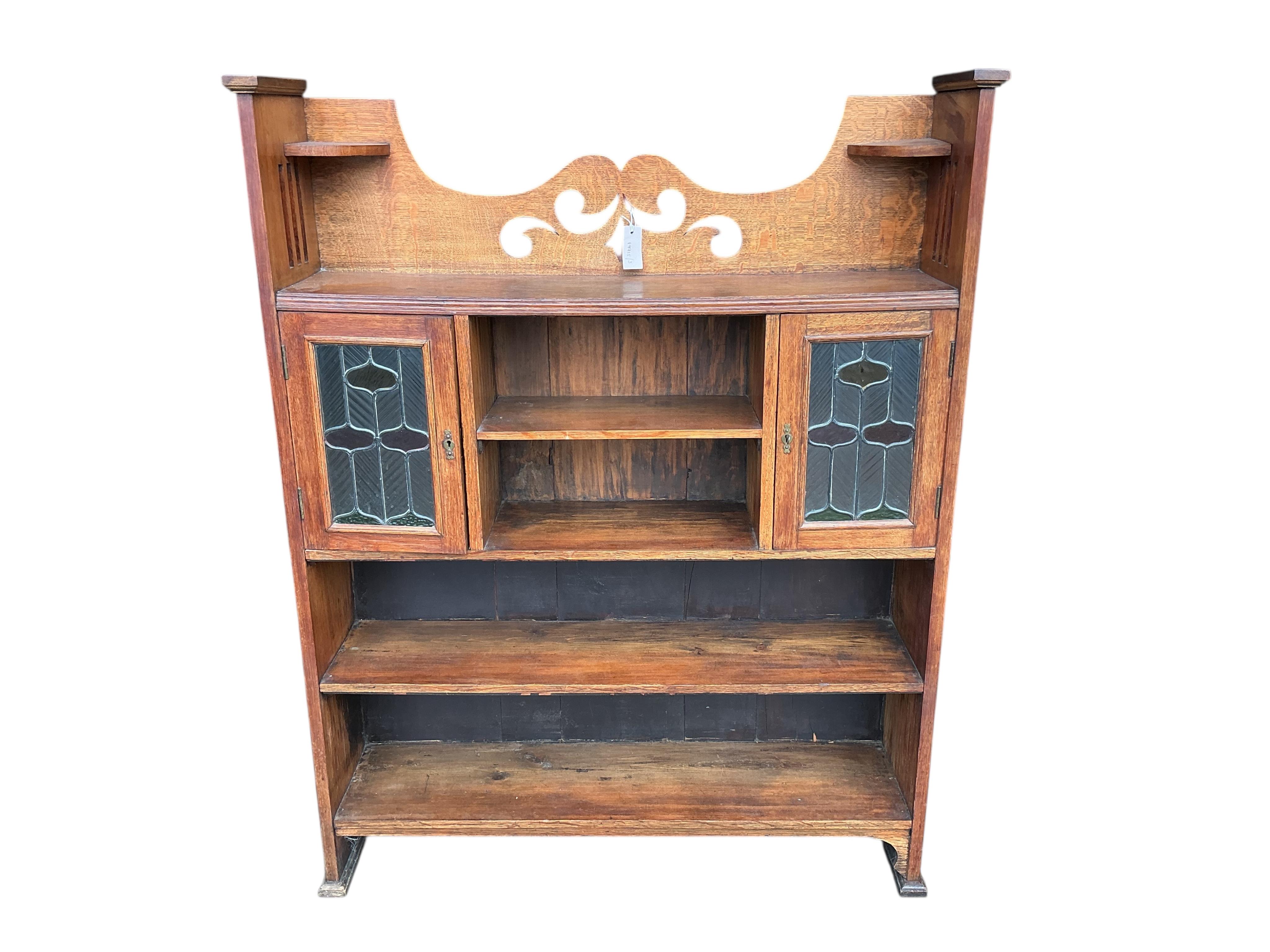 An Arts & Crafts oak open bookcase with stained leaded glass doors, width 108cm, depth 24cm, height 137cm